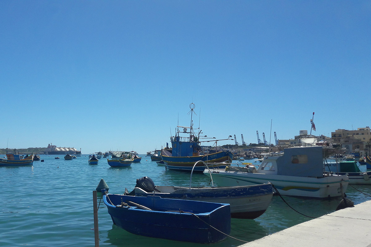 Fishing boats in Marsaxlokk harbor, Malta, with a view of the Delimara power station.