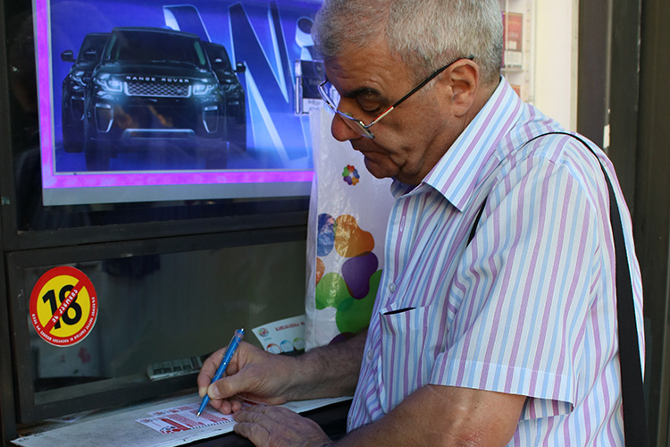 Sporadic lottery player David Pantsulaia, 65, buys a Georgian lottery ticket at a kiosk on Chavchavadze Avenue in Tbilisi. He says he dreams of winning the jackpot. (Photo: Tatuli Omiadze, iFact.ge)